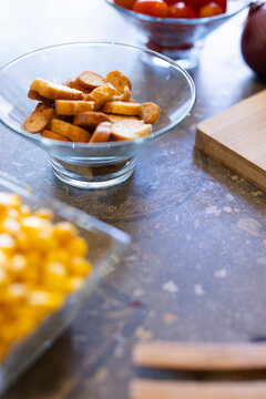 At home, Close-up of snacks in glass bowls, featuring croutons, tomatoes, and corn