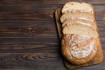Freshly baked bread slices on cutting board against white wooden background. top view Sliced bread