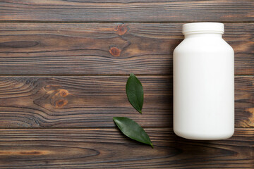 supplement pills with medicine bottle health care and medical top view. Vitamin tablets. Top view mockup bottle for pills and vitamins with green leaves, natural organic bio supplement, copy space