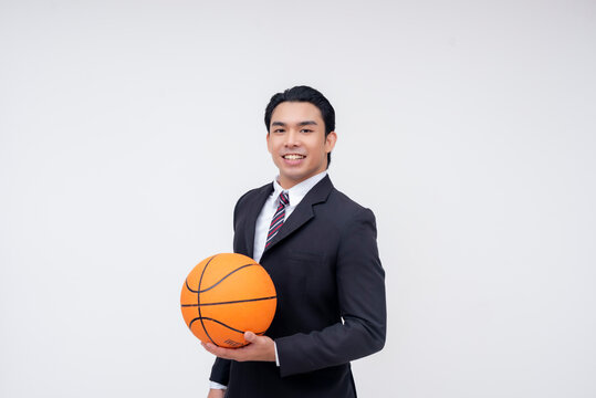 A confident and talented young asian business executive in a full suit holding a basketball. An MVP or pro basketball player in formal attire. Isolated on a white background.