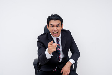 An angry young asian business executive sitting on an office chair, screaming at someone, yelling you're fired! Isolated on a white background.