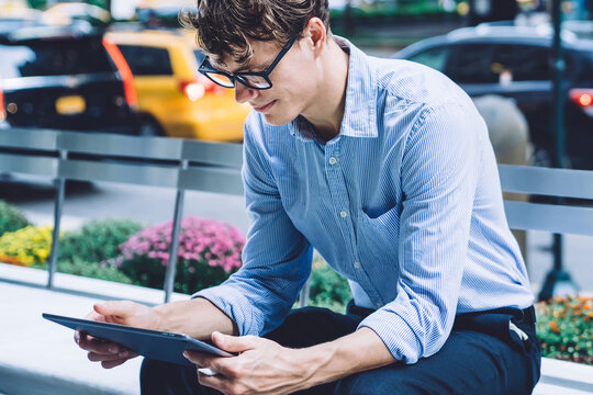 Serious male owner reading received notification with receipt on touch pad during time in financial district, businessman in formal wear using banking app digital tablet for checking balance account