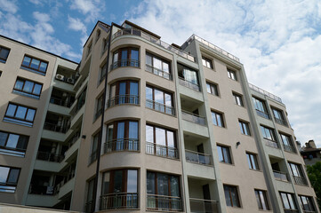 Modern residential building showcasing curved balcony design in a vibrant urban neighborhood under...