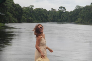 mulher com vestido claro e chapéu na beira de rio em hotel de selva em alta floresta, mato grosso 