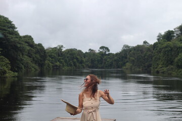 mulher com vestido claro e chapéu na beira de rio em hotel de selva em alta floresta, mato grosso 