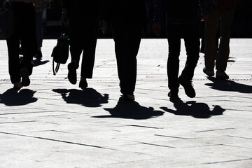 Obraz premium Black silhouettes and shadows of people on the street. Crowd walking down on sidewalk, concept of pedestrians, crime, society, city life