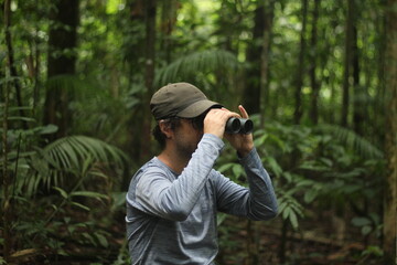 homem com binóculo em trilha na floresta amazônica