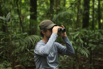 homem com binóculo em trilha na floresta amazônica
