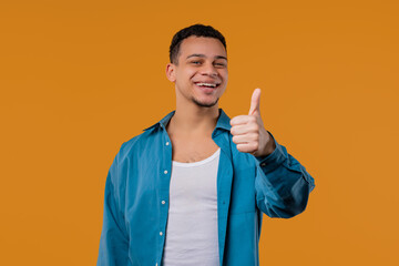 Positive stylish biracial man with LIKE sign, thumbs up gesture. Happy hipster.