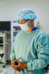 Surgeon preparing for an operation in a hospital. A dedicated surgeon in scrubs and gloves is...