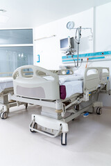 A hospital bed with a clock on the wall. The bed is empty and the room is clean