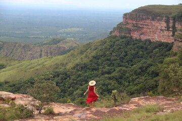 mulher de vestido vermelho e chapéu no mirante Alto do Céu, na Chapada dos Guimarães, Mato...