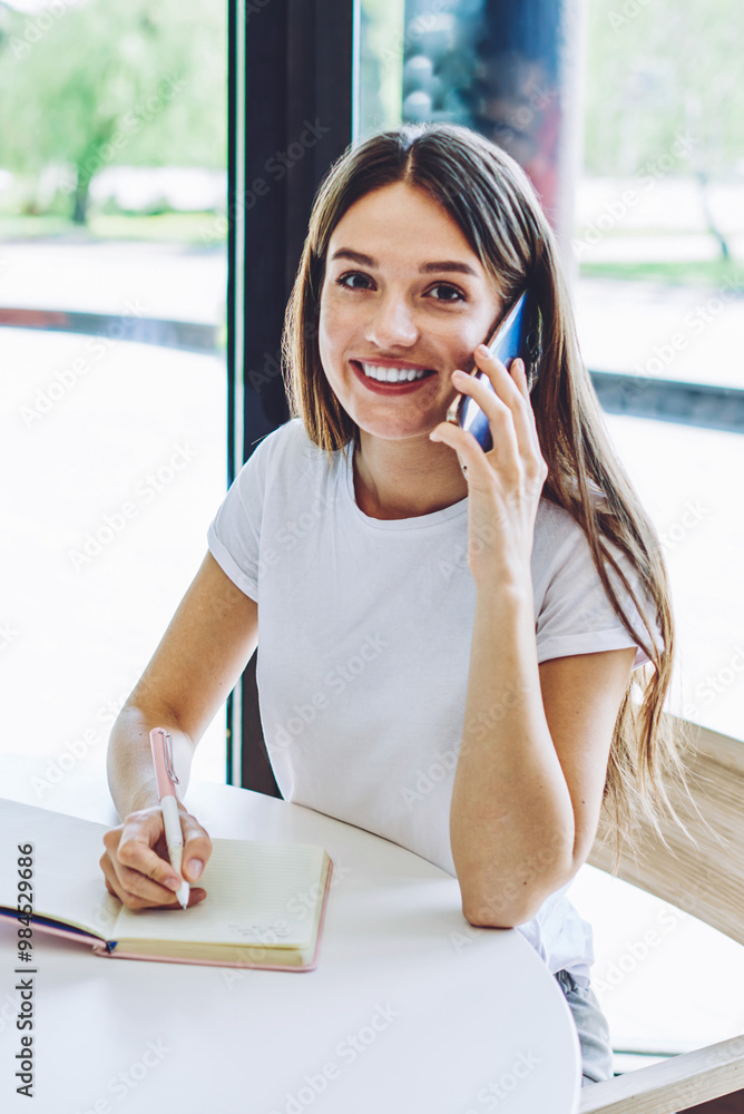 Poster portrait of cheerful female blogger creating publication for social network using textbook for makin