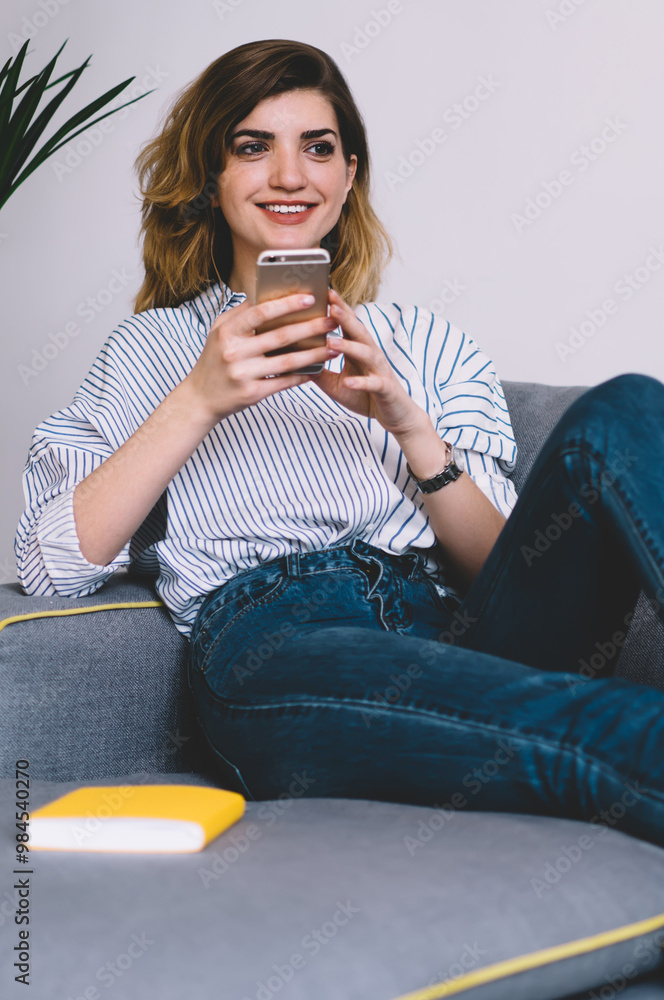 Poster happy young woman enjoying free time at home lying on comfortable stylish couch and browsing social 