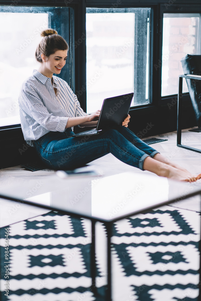 Poster happy smiling hipster girl watching funny movie on website with comedy content while sitting on floo