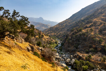 A scenic view of a mountainous valley with a river winding through Sequoia National Park,...