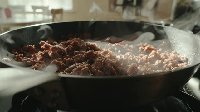 Ground meat in skillet on stove steaming 