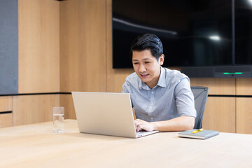 Fototapeta premium At office, Working on laptop, asian man sitting at conference table with notebook and glass of water