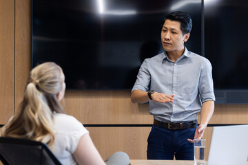 Obraz premium Business meeting, asian man presenting to colleague in modern office setting