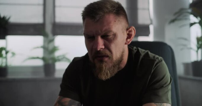 Close up of depressed military man with PTSD crying during psychological rehabilitation. Male soldier shares traumatic experience with psychotherapist or psychologist. Post traumatic stress disorder.