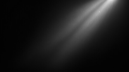 A black and white photograph of a beam of light cutting through the darkness, illuminating floating dust particles