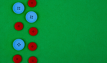 Blue and red plastic buttons on green fleece fabric