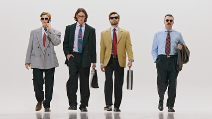 Posing confidently with briefcases, men shows power and determination in oversized suits against white studio background. Concept of corporate culture, business and style, leadership. Ad
