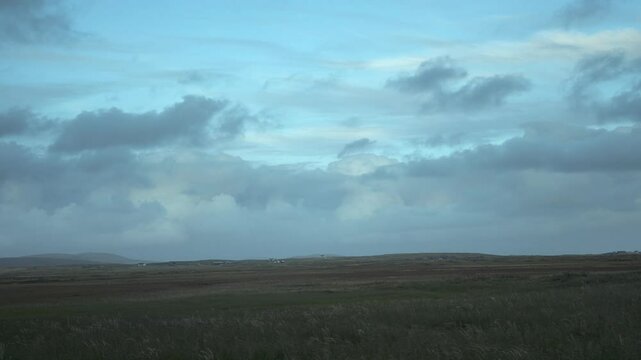 4K Time-Lapse of moving clouds over field at sunset. The Isle of North Uist, Scotland