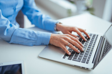 Person Typing on a Laptop in a Bright Office