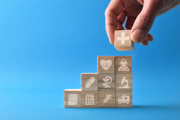 Medical care concept with hand stacking cubes with symbols front