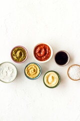 Set of bowls with sauces pesto salsa mustard and others, top view. Food background