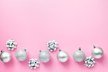 New Years festive frame of glittery silver balls and decorations. Above view. Pink background.