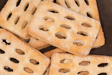 Flat flaky cookies on a brown dish close-up