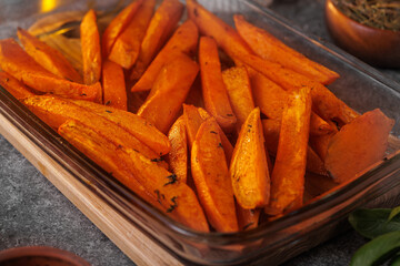 Appetizing sweet potatoes, cut into slices, baked in the oven with spices and butter close-up. Healthy vegan food. Selective focus