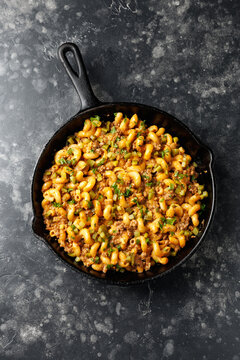 Naklejki Cheeseburger Pasta with ground beef, melted cheese and gherkins in a iron cast pan