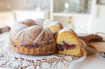 Delicious homemade whole plum bundt cake with cross section view isolated on kitchen counter