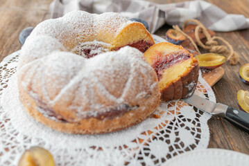 Delicious homemade plum bundt cake on rustic and wooden table background.