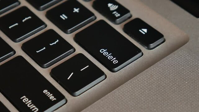 Motion close up finger click delete button. Concept of digital and delete from storage. The index finger presses the delete key on the laptop keyboard.