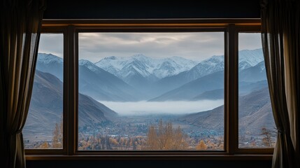 Scenic mountain view framed by a window, showcasing mist and autumn foliage.