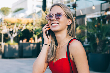 Cheerful blonde chatting on phone on street