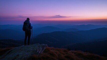 Obraz premium A hiker gazes at a serene mountain landscape during twilight.