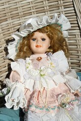 Porcelain vintage doll with curly hair wearring beautiful dress.