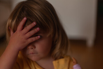 Fototapeta premium a beautiful two-year-old blonde girl covering her eyes