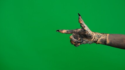 Creepy halloween monster hand in black paint with nails moving pointing finger at side, isolated on chroma key green screen background, workspace mockup.