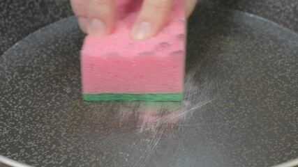 Sponge for washing dishes in scratched Teflon non stick coated pan. Dangerous chemicals in cookware. Pan peeling off.