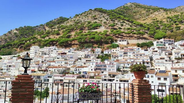 Panoramic static view of typical andalusian white village Mijas located on the Costa del Sol, Spain. A lot of white washed houses, mountains and pine forest in the background. Sunny weather, blue sky.