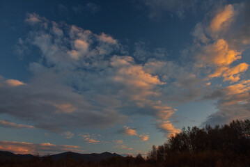 Russia, south of Western Siberia. Panoramic view of the evening sky with the setting sun and colorful clouds.