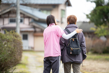 ヘルパーに付き添われて歩く高齢者女性