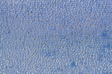 Blue water droplets on a piece of polycarbonate. Abstract background