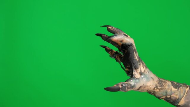 Creepy halloween monster hand in black paint with nails crawling scratching fingers gesture, isolated on chroma key green screen background, workspace mockup.